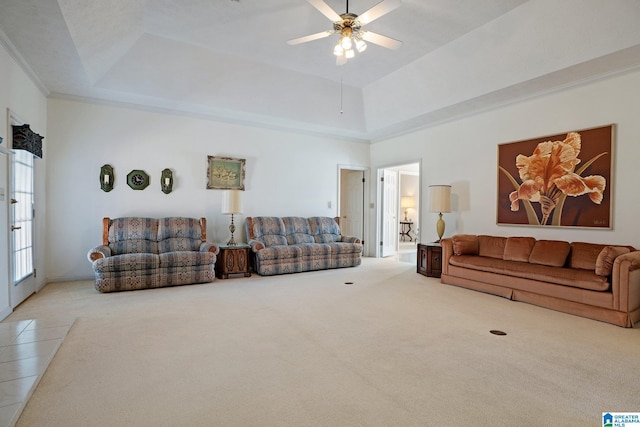 carpeted living area featuring a raised ceiling, ornamental molding, a towering ceiling, and ceiling fan