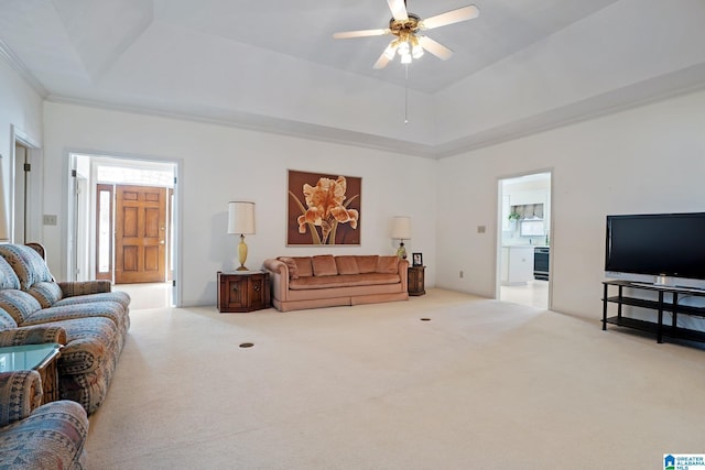 living area with ceiling fan, a raised ceiling, and carpet