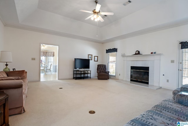 living area with a raised ceiling, visible vents, and carpet floors