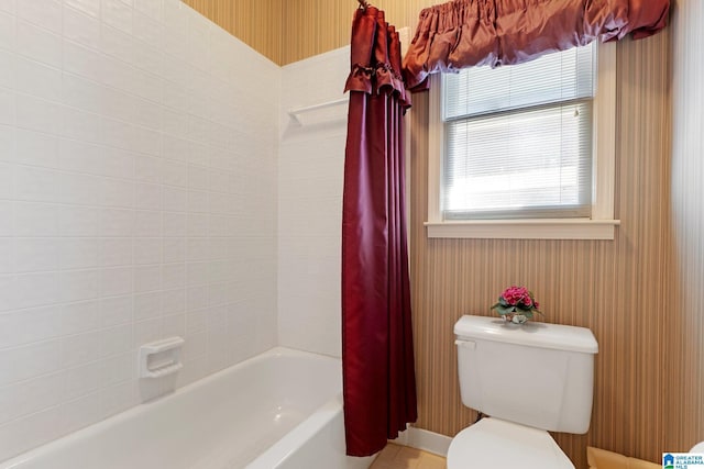 bathroom with wallpapered walls, toilet, and shower / bath combo with shower curtain