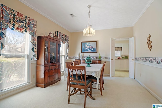 dining area featuring an inviting chandelier, a healthy amount of sunlight, crown molding, and light carpet