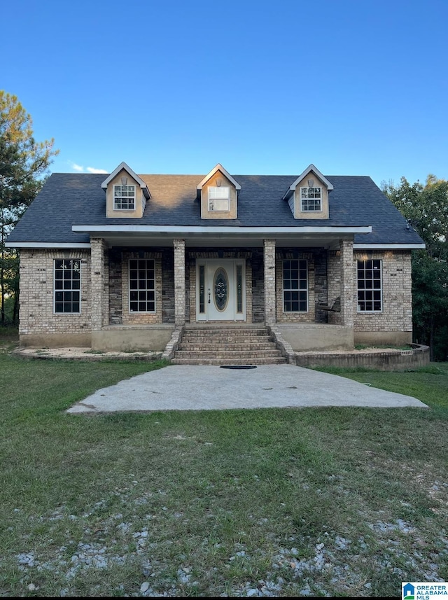 view of front of house with brick siding, covered porch, and a front lawn