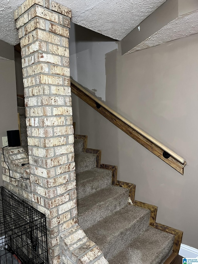 stairway with a textured ceiling and baseboards