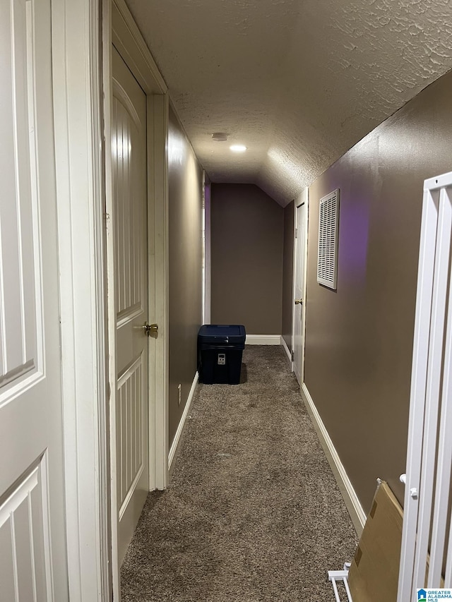 hallway with carpet, baseboards, visible vents, lofted ceiling, and a textured ceiling