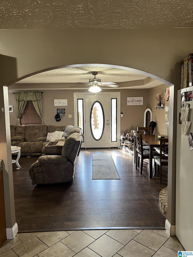 living area with arched walkways, a textured ceiling, and wood finished floors