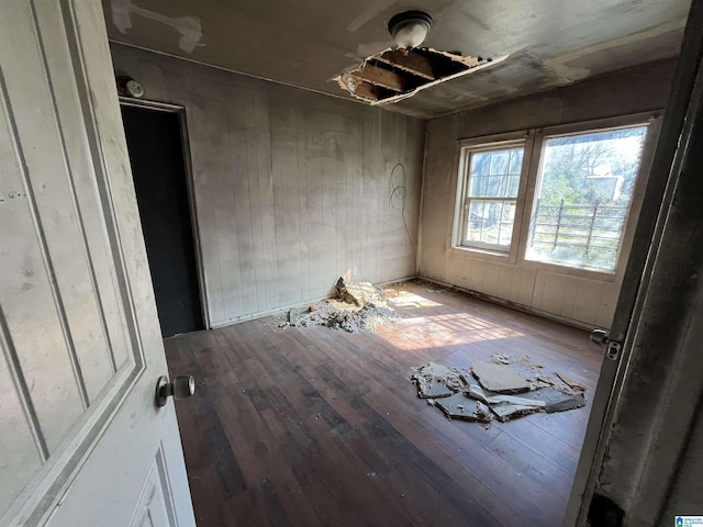 unfurnished room with wood-type flooring and wooden walls