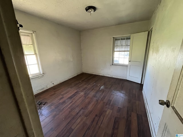 empty room with plenty of natural light and dark wood-type flooring