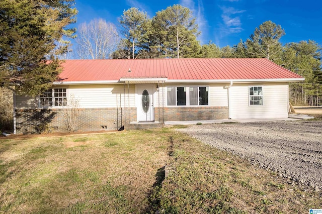 single story home with a front yard, brick siding, and metal roof