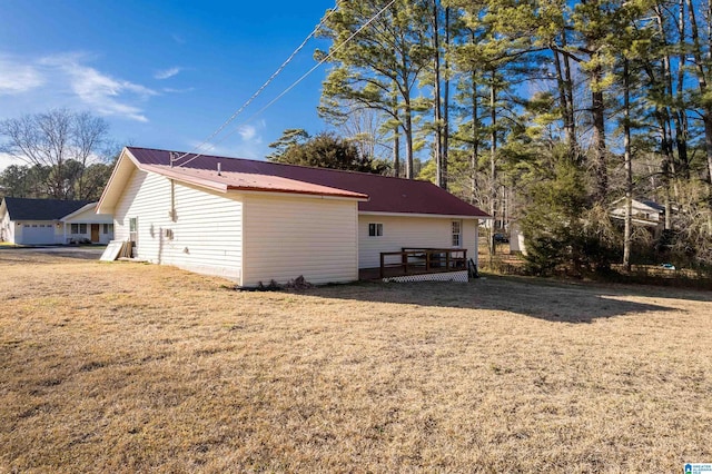 rear view of property with a wooden deck, a lawn, and metal roof