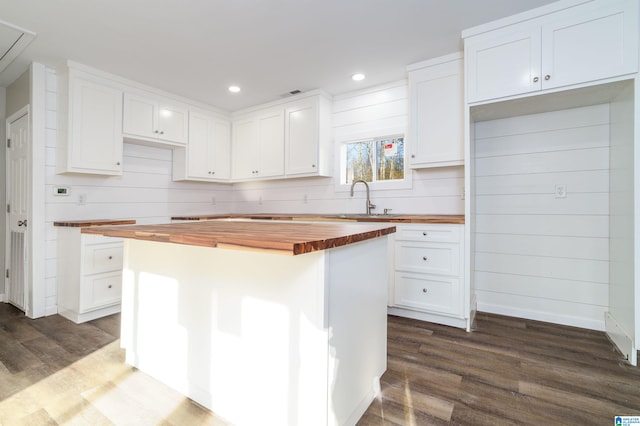 kitchen featuring a sink, a center island, white cabinetry, wooden counters, and dark wood-style flooring