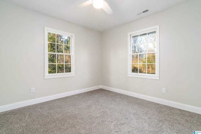 carpeted spare room featuring visible vents, baseboards, and a ceiling fan