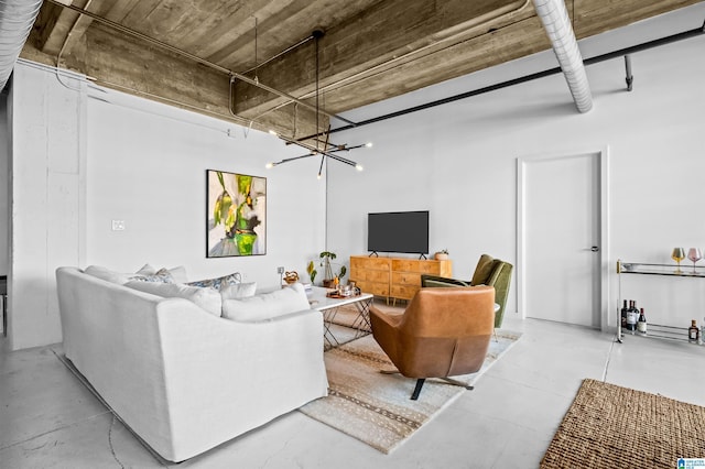 living area with a notable chandelier and concrete flooring