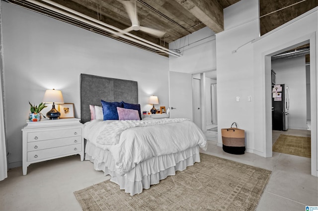 bedroom with a high ceiling and freestanding refrigerator