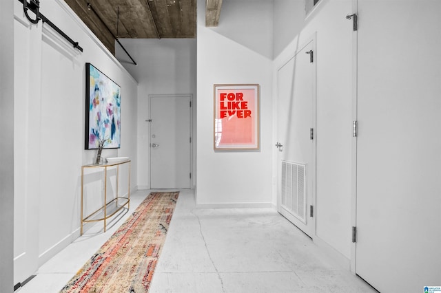 hallway with a barn door, baseboards, and visible vents
