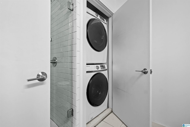 clothes washing area with light tile patterned flooring and stacked washer and dryer