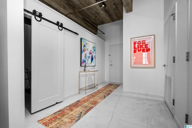 interior space with a barn door, baseboards, visible vents, and concrete flooring