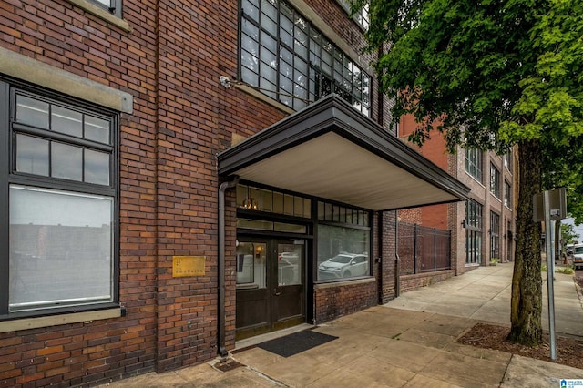 view of exterior entry featuring french doors and brick siding