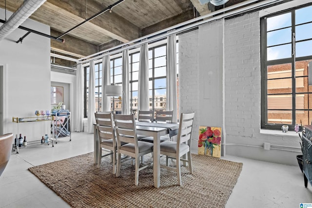 dining room with brick wall, plenty of natural light, and concrete floors
