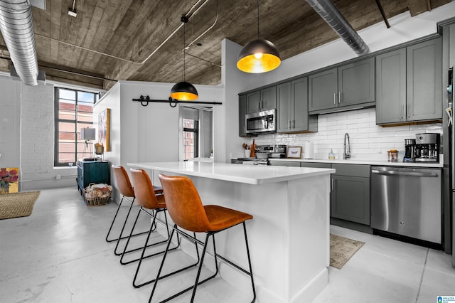 kitchen featuring concrete floors, a sink, light countertops, appliances with stainless steel finishes, and a center island