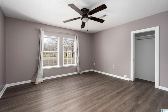 unfurnished bedroom with baseboards, visible vents, dark wood-style flooring, ceiling fan, and a textured ceiling