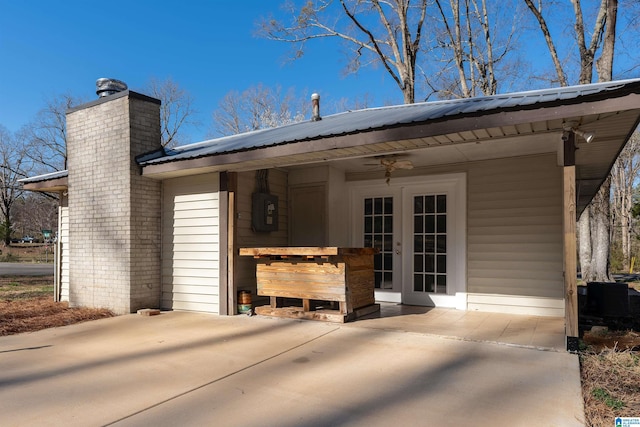 back of property with ceiling fan, french doors, a chimney, and metal roof