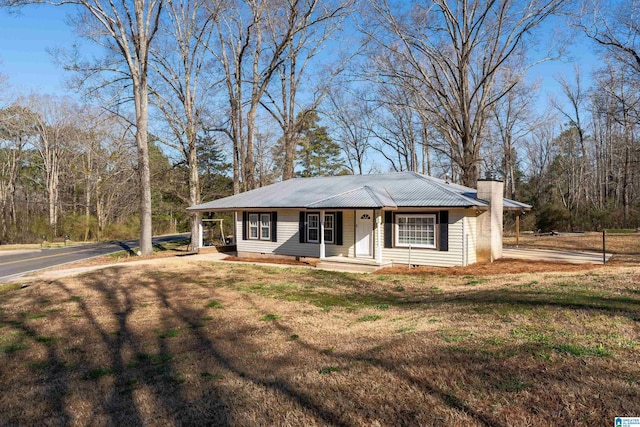 single story home featuring metal roof, a front lawn, and a chimney