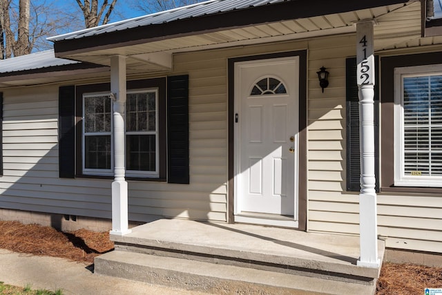 entrance to property featuring a porch, crawl space, and metal roof