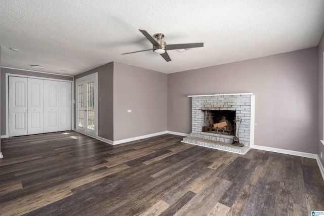 unfurnished living room featuring a ceiling fan, wood finished floors, baseboards, a textured ceiling, and a brick fireplace