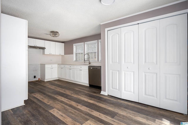 kitchen featuring white cabinetry, dark wood-style flooring, a sink, under cabinet range hood, and stainless steel dishwasher