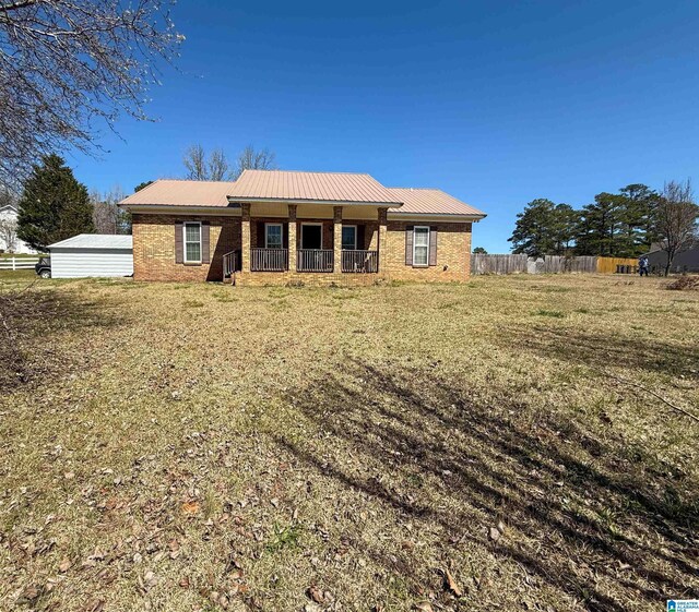 view of front facade with covered porch, fence, brick siding, and metal roof