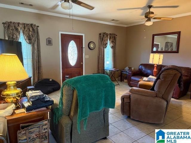 living room featuring visible vents, a ceiling fan, and ornamental molding