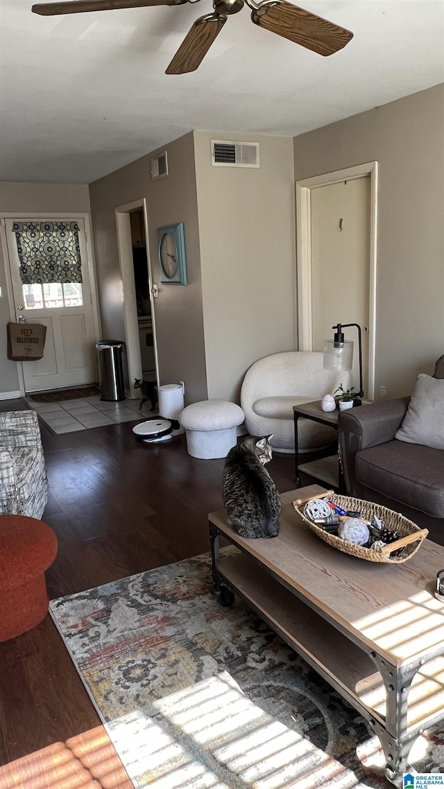 living area featuring heating unit, wood finished floors, visible vents, and ceiling fan