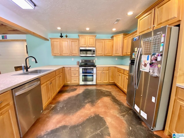 kitchen featuring unfinished concrete floors, a sink, light brown cabinetry, stainless steel appliances, and a textured ceiling