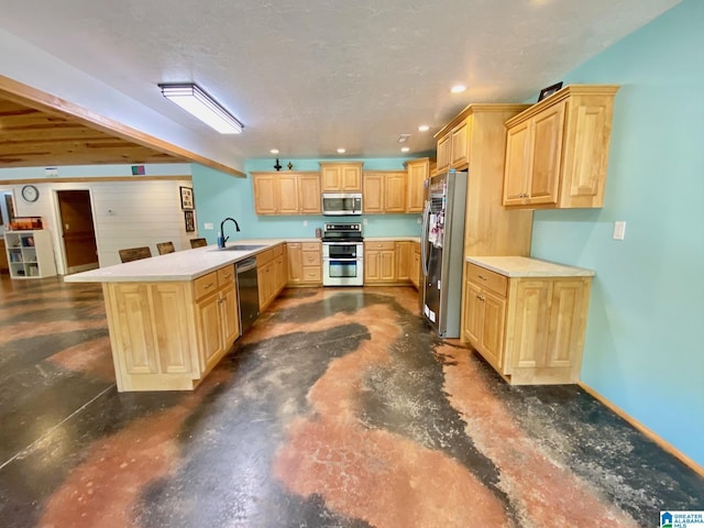 kitchen featuring light brown cabinets, a sink, appliances with stainless steel finishes, a peninsula, and light countertops