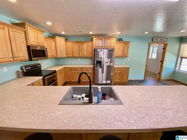 kitchen featuring recessed lighting, a sink, stainless steel appliances, light countertops, and a textured ceiling