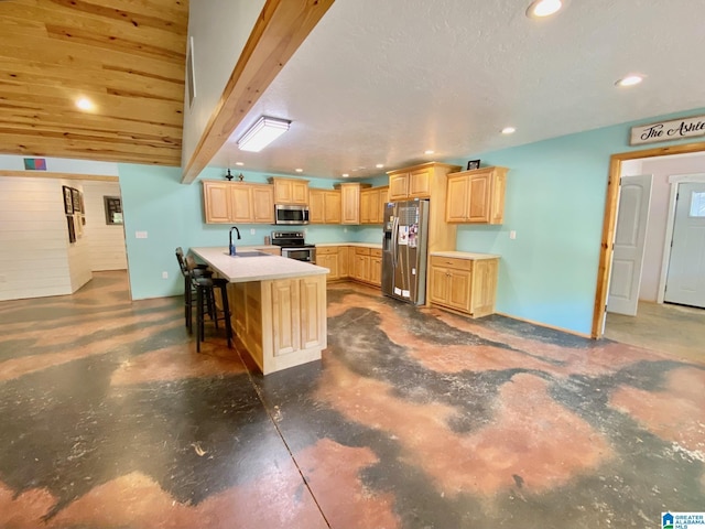 kitchen with a sink, light brown cabinets, concrete flooring, and stainless steel appliances