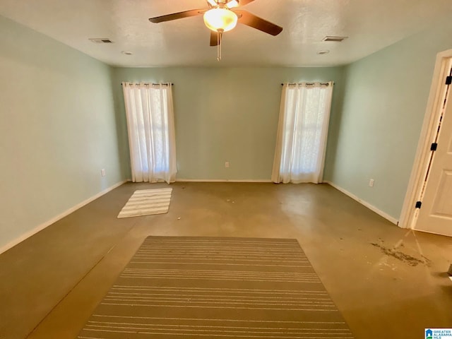 empty room with visible vents, a ceiling fan, and baseboards