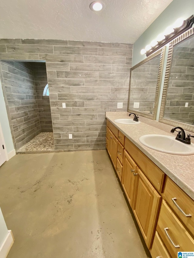 bathroom with a textured ceiling, double vanity, concrete flooring, and a sink