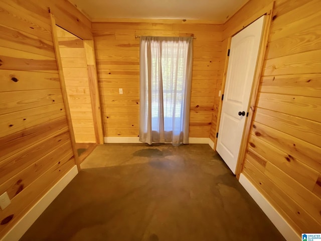 entryway featuring baseboards, concrete floors, and wood walls