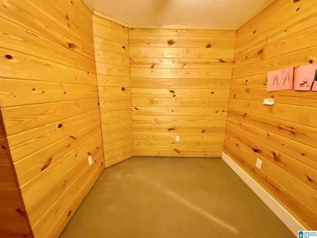 unfurnished room featuring wood walls and finished concrete floors