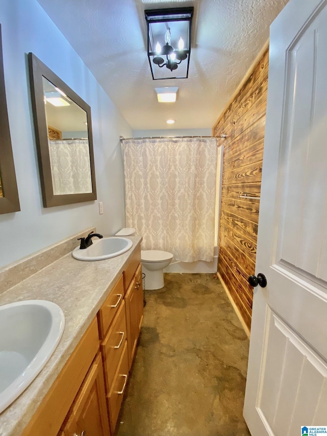 bathroom featuring double vanity, a textured ceiling, toilet, and a sink