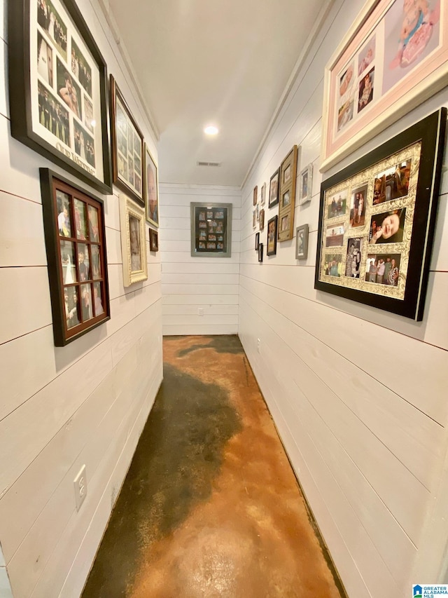 corridor featuring visible vents, concrete floors, and wood walls