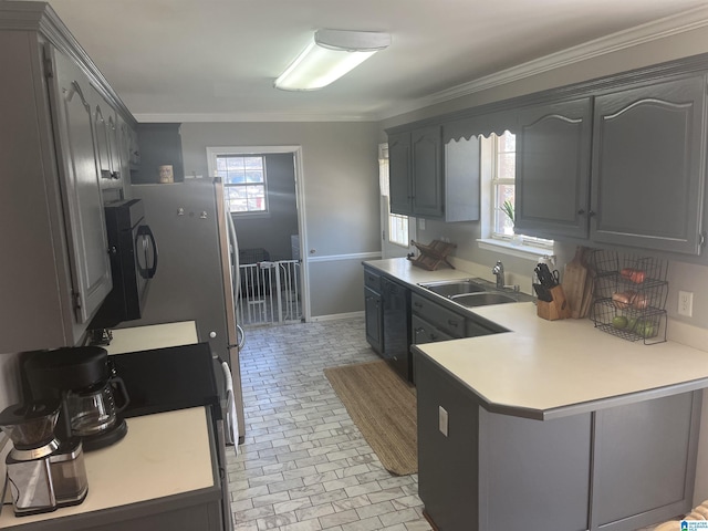 kitchen featuring a sink, a peninsula, black microwave, light countertops, and stove