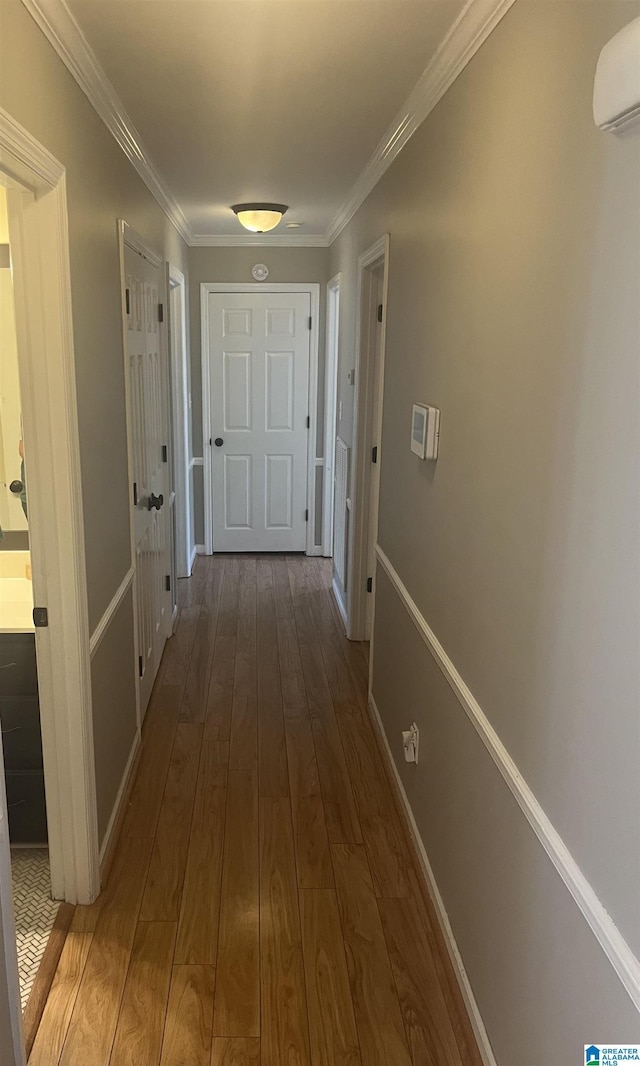 hall with baseboards, crown molding, a wall unit AC, and wood finished floors