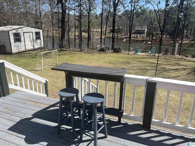 deck with an outbuilding, a storage shed, a water view, and fence