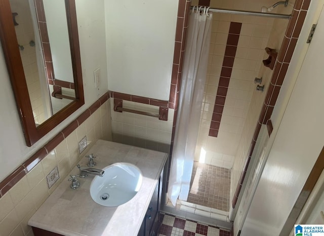 bathroom with tiled shower, tile walls, vanity, and a wainscoted wall