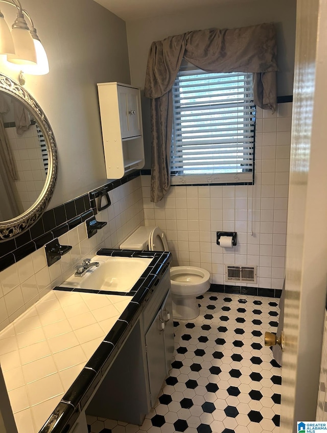 bathroom featuring vanity, tile walls, toilet, and visible vents