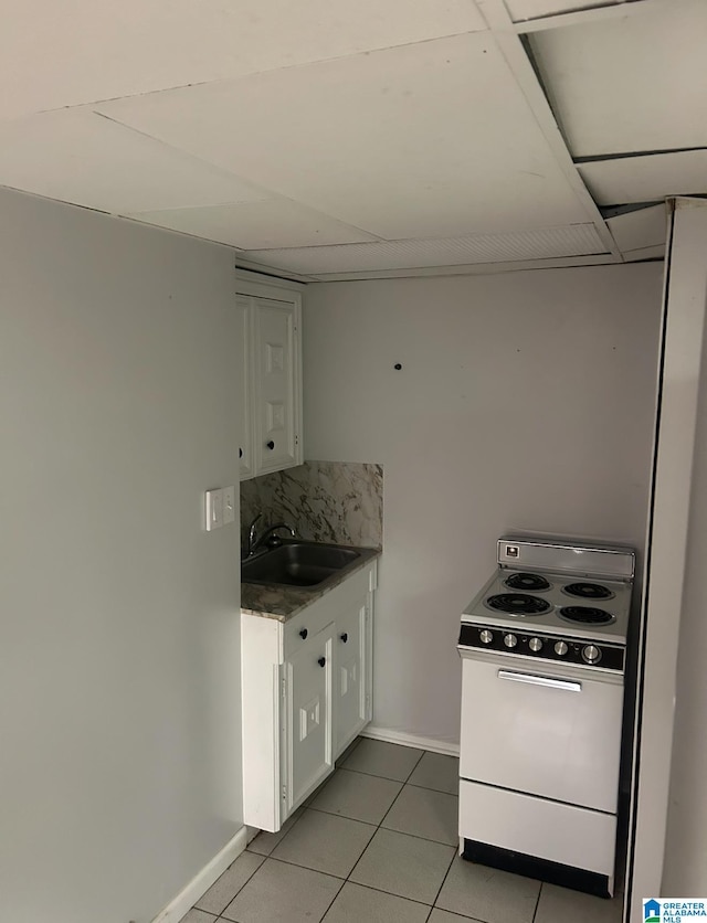 kitchen with a sink, white cabinets, light tile patterned floors, and white range with electric cooktop