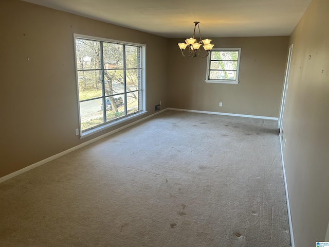 unfurnished room featuring carpet flooring, baseboards, and a chandelier