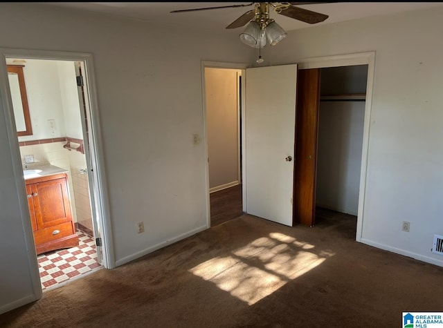 unfurnished bedroom featuring visible vents, carpet floors, a closet, ensuite bathroom, and tile walls